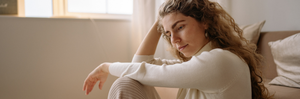 Woman sitting gazing down looking thoughtful