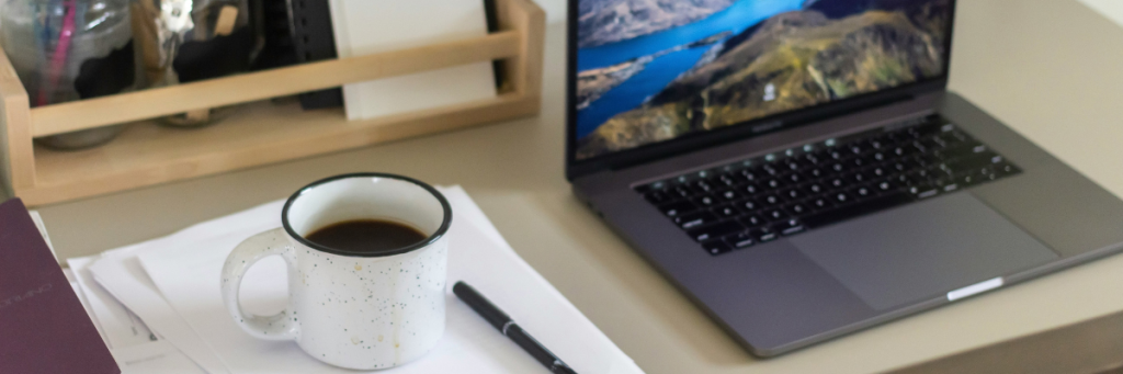 Table with laptop, pen, notebook and coffee